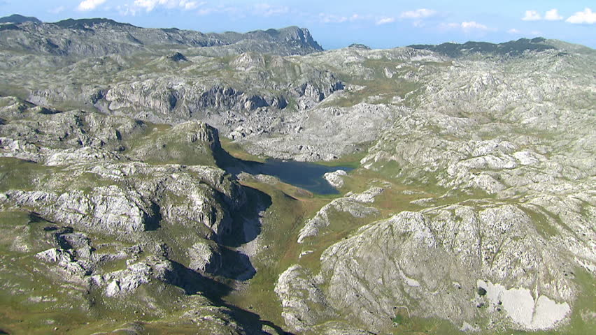 Rocky terrain of Dinaric Alps with beautiful small lake in the center