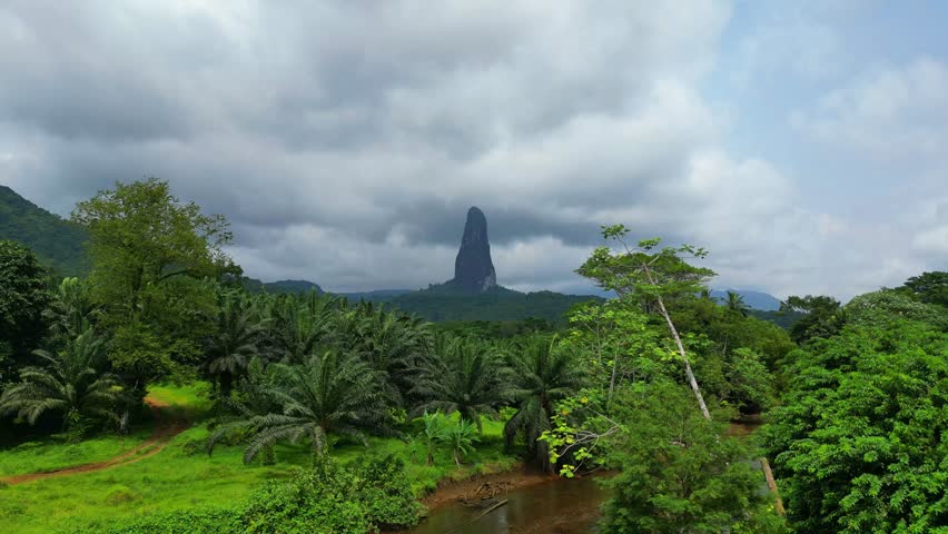 Aerial shot low over the Caue river, and rising towards the Pico Cao Grande in Sao Tome,Africa