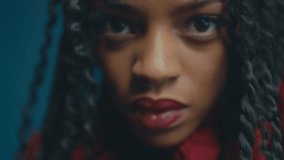 Artistic black woman with braided hair bushes back long strands wearing fluffy red ruffled dress as light dances across body - Powered by Shutterstock - Get 15% off with code: PIKWIZARD15