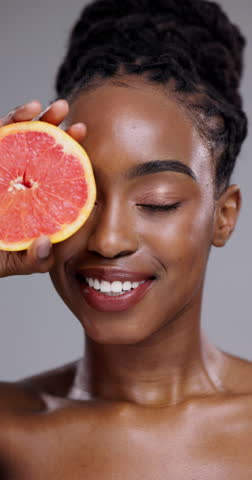 Grapefruit, beauty and face of black woman in studio for vitamin c benefits, nutrition or glow on grey background. Portrait, model or citrus fruits for healthy skincare, sustainable cosmetics or diet