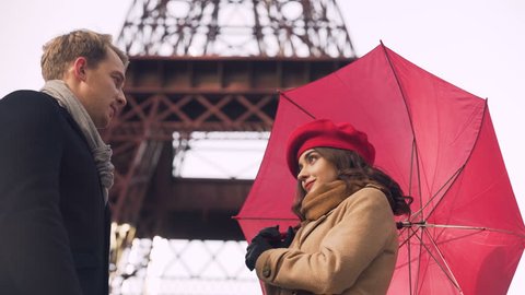 Beautiful young couple tenderly kissing under umbrella, romantic date in Paris