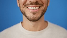 A smiling young hispanic man poses for a close-up portrait against an isolated blue outdoor background. - Powered by Shutterstock - Get 15% off with code: PIKWIZARD15