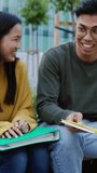Multiracial college students talking at campus. Asian teenage classmate friends resting in city park while having a conversation after classroom. Education and people concept. Vertical HD video.