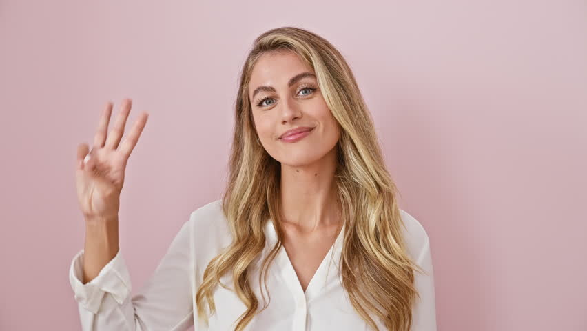 Cheerful young blonde woman donning a shirt, confidently pointing up three fingers with smiling expression, signaling the number three for a happy concept over an isolated pink background. Royalty-Free Stock Footage #3459152323