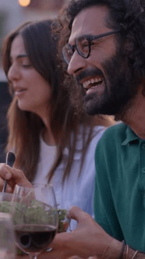 Vertical. Smiling people having fun at reunion of friends BBQ food and beverage. Couple eating and drinking happiness on sunset at a terrace. Laughing group of multiracial friends celebrating a meal Video Stok
