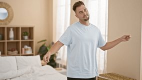 Smiling man stretching in his bedroom, expressing wellness and a casual lifestyle at home.