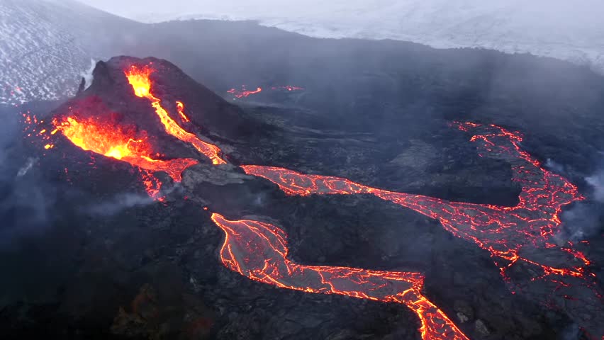 Aerial cinematic footage captured by a 4K drone showcases the unique sight of two volcanoes positioned side by side, both expelling lava rapidly as molten streams cascade downwards.