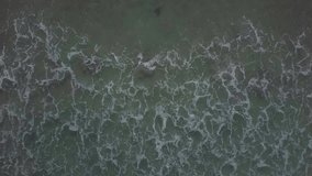 Overhead video of crashing waves on the shoreline beach. Tropical beach surf. Abstract aerial ocean view, Couple lying on famous pink beach in Komodo national park. Turquoise mint color clear water, 