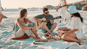 Friends, picnic on beach and guitar for singing with fun outdoor, reunion and people with celebration. Summer, holiday with social gathering or hangout, friendship and party with instrument and music - Powered by Shutterstock - Get 15% off with code: PIKWIZARD15