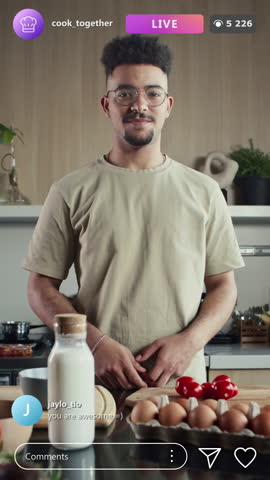 Vertical shot of young food blogger telling what you need for cooking during live stream on social media, animated comments and likes popping up on screen