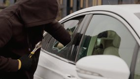 A white car in the parking lot with the window broken by a thief using a key as he reaches through the hole in the broken window to retrieve a woman's aba bag, daring act of theft - Powered by Shutterstock - Get 15% off with code: PIKWIZARD15