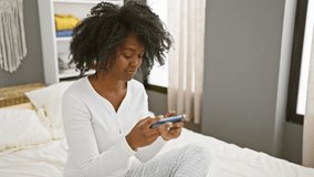 African american woman playing video game in bedroom, showing joy and excitement indoors.