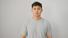 Handsome young chinese man in a cool, simple t-shirt casually isolated on a white wall. his earnest, trusting gaze meets the camera, a serious expression pulling at his features. - Powered by Shutterstock - Get 15% off with code: PIKWIZARD15