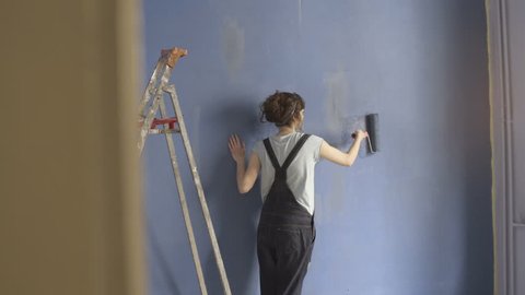 Girl painting blue wall  with roller