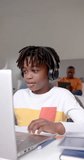 Vertical video of african american boy using laptop for online lesson at home, slow motion. Childhood, communication, education, learning and domestic life, unaltered.