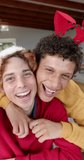 Vertical video of diverse gay male couple having video call at home, slow motion. Lifestyle, christmas, celebration, togetherness, communication and dometic life, unaltered.