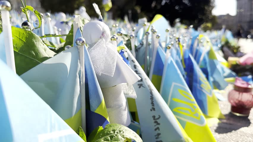 Many small flags of Ukraine with names of the dead war against russia. Memorial of the fallen soldiers, children, women in the center of Kyiv. Concept of tragedy and misfortune. Closeup