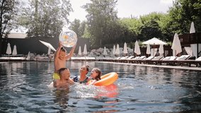 Parents with children playing with ball in swimming pool water in sunny summer. Active family vacation at a beach resort. Happy smiling family holiday. Fun game - Powered by Shutterstock - Get 15% off with code: PIKWIZARD15