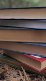 Stacked books in the forest. The concept of learning, reading, and knowledge. Close-up. Blurred background. Vertical video