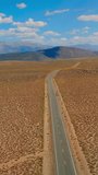 Road passing through the plain deserted landscape of United States. Picturesque mountains of itinerary for California to Nevada at sunny daytime. Vertical video.