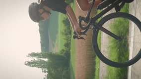 Cycling and triathlon. Woman cycling on bicycle uphill at sunset. Intense cycling training. Professional cyclist ride bicycle through picturesque countryside landscape. Vertical video
