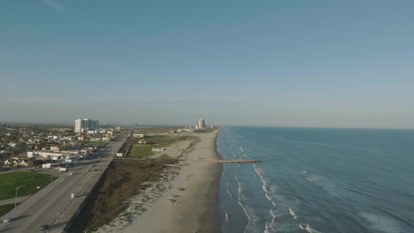 An aerial establishing shot of the east end of Galveston Island along Seawall Blvd, at sunset.