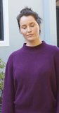 Vertical video of happy caucasian woman in purple sweater smiling in front of house in garden. Lifestyle,relaxation,free time and domestic life,unaltered.