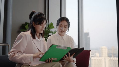 Young asian business woman hold the clipboard and to show or consult or discussion to the colleague and shaking hands in the home office in night, Talk about investments, finances, profits and losses: stockvideo