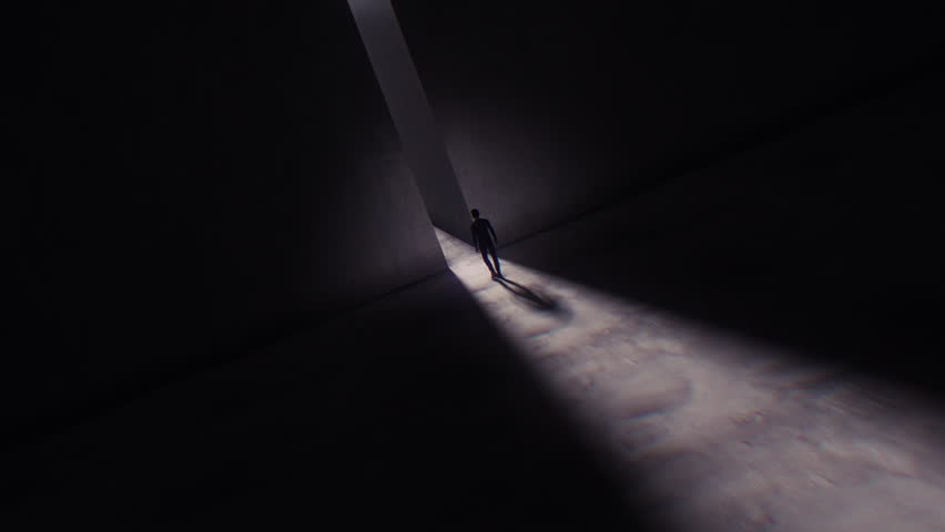 A darkened scene where we see a man walking towards a bright light coming from a tall opening in a huge stone marbled wall. Royalty-Free Stock Footage #3459860323