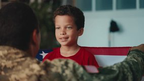 A military dad enfolds his son in American flag, teaching him to love homeland - Powered by Shutterstock - Get 15% off with code: PIKWIZARD15