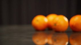 A group of oranges are featured in a video where they are being splashed with water and falling into water on a black surface. The oranges are also shown sitting on a table with water drops - Powered by Shutterstock - Get 15% off with code: PIKWIZARD15