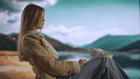 Female working from distance and travelling. Young woman freelancer resting near mountain lake, wearing headphones, listening music on smartphone. - Powered by Shutterstock - Get 15% off with code: PIKWIZARD15