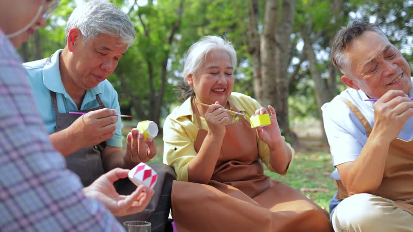 Art activities for the elderly. A group of elderly people sit and paint pots in the garden outside. They are happy. Living happily in retirement. art therapy. Elderly community