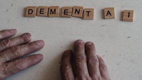 concept of dementia in a pensioner. the hands of an old man make up the inscription dementia from wooden blocks on the table. senile diseases. dementia treatment