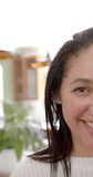 Vertical video of half face of happy biracial woman with straight hair smiling in sunny kitchen. Lifestyle, wellbeing, free time and domestic life, unaltered.