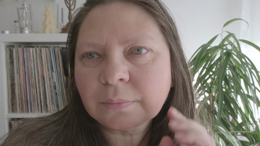 self-aware woman 50 years of age, takes moment to assess her facial features, particularly jowls, reflecting on natural process of aging and considering options for maintaining youthful appearance Royalty-Free Stock Footage #3460064113