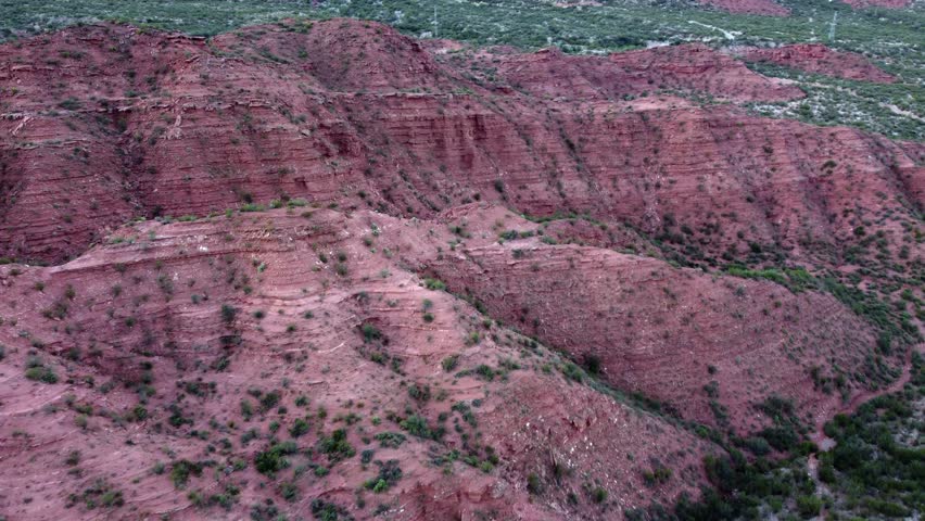 Sedimentary rock cliffs rich in iron oxide glow red, Argentina aerial