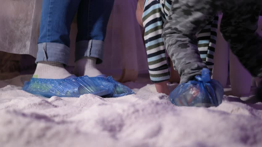 Young mothers with young sons rest in a salt room. Large legs in protective bags