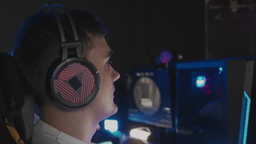Caucasian teen gamer in headset playing PC video game at computer club. E-sport championship tournament, cyber sport team. Multiplayer online competition tactical first-person shooter. Close up side