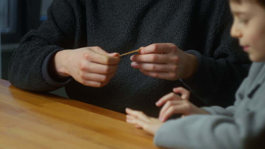 Father applying a band aid on his son's injured hand and caressing his head while sitting in the kitchen at home.