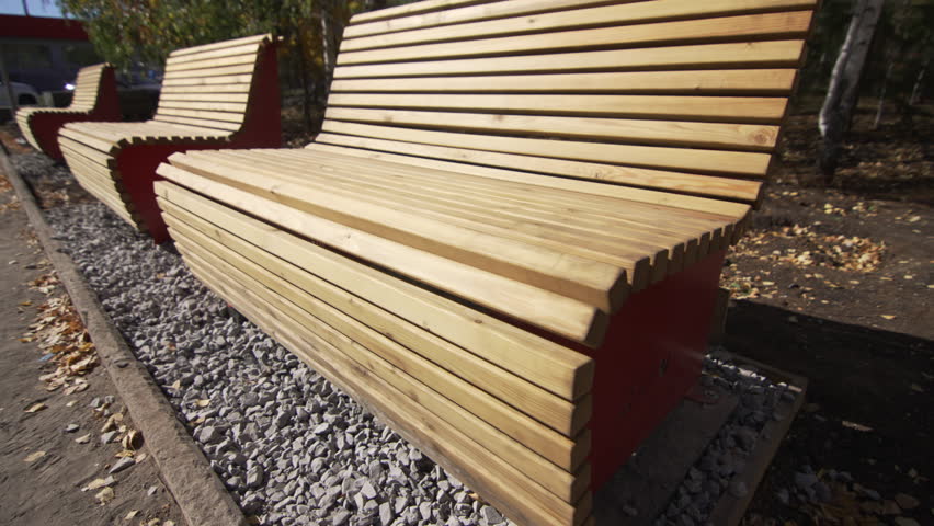 Wooden benches stand in park and provide place to rest. Comfortable place for visitors to take break during walk and enjoy wonderful view