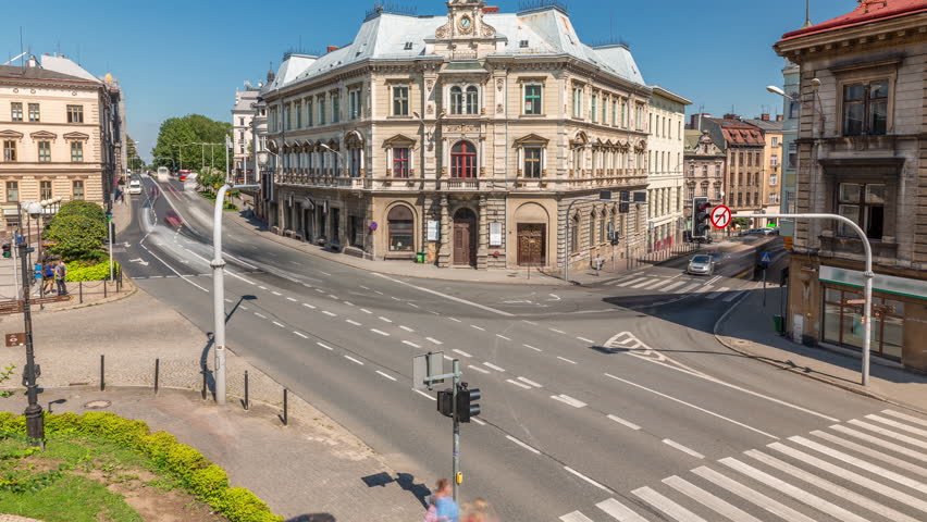 Busy traffic on intersection near Chrobry Square in Bielsko-Biala timelapse, Poland. Historic buildings aerial view from Sulkowski Castle. People crossing the road. Sunny day with a blue sky