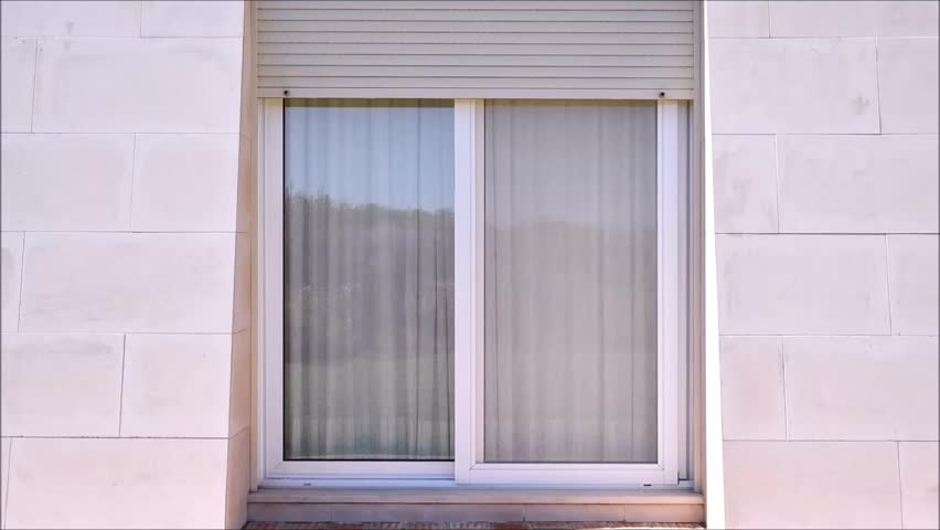 Outside view of electric security shutters on a house rolling down or closing