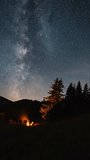 Vertical video of milky way galaxy stars over forest and people barbecue campfire nature, Astronomy Time lapse