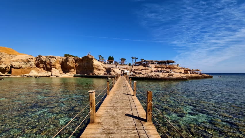 Walking on wooden footbridge to cross a gulf of shallow water.