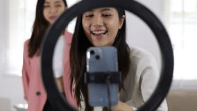Young Asian woman and friends using smartphone to create her own dance video. Happy beautiful woman dancing moving rhythmically while listening to music song. Woman practicing dancing at home.