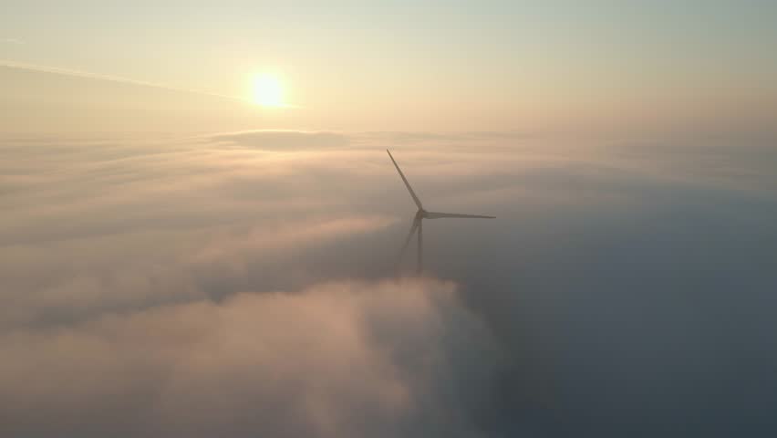 Aerial view of wind turbines spinning above the clouds during sunrise, Netherlands