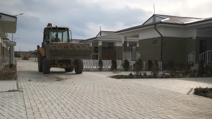 Wheel loader. Backhoe loader driving along the street of suburban village to carry out construction work on a new facility. Close up. Construction equipment.