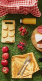 Vertical video of fresh food, basket and gingham tablecloth with copy space on grass. Picnic day, leisure time, alfresco eating and lifestyle concept.
