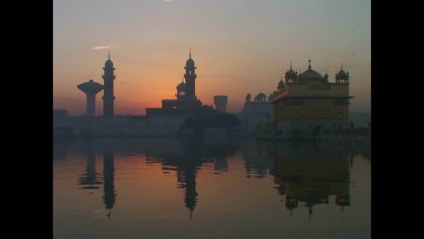 INDIA - 1999 - Distant view of the sun setting behind India's Golden Temple and its sacred pool. Royalty-Free Stock Footage #3460596299
